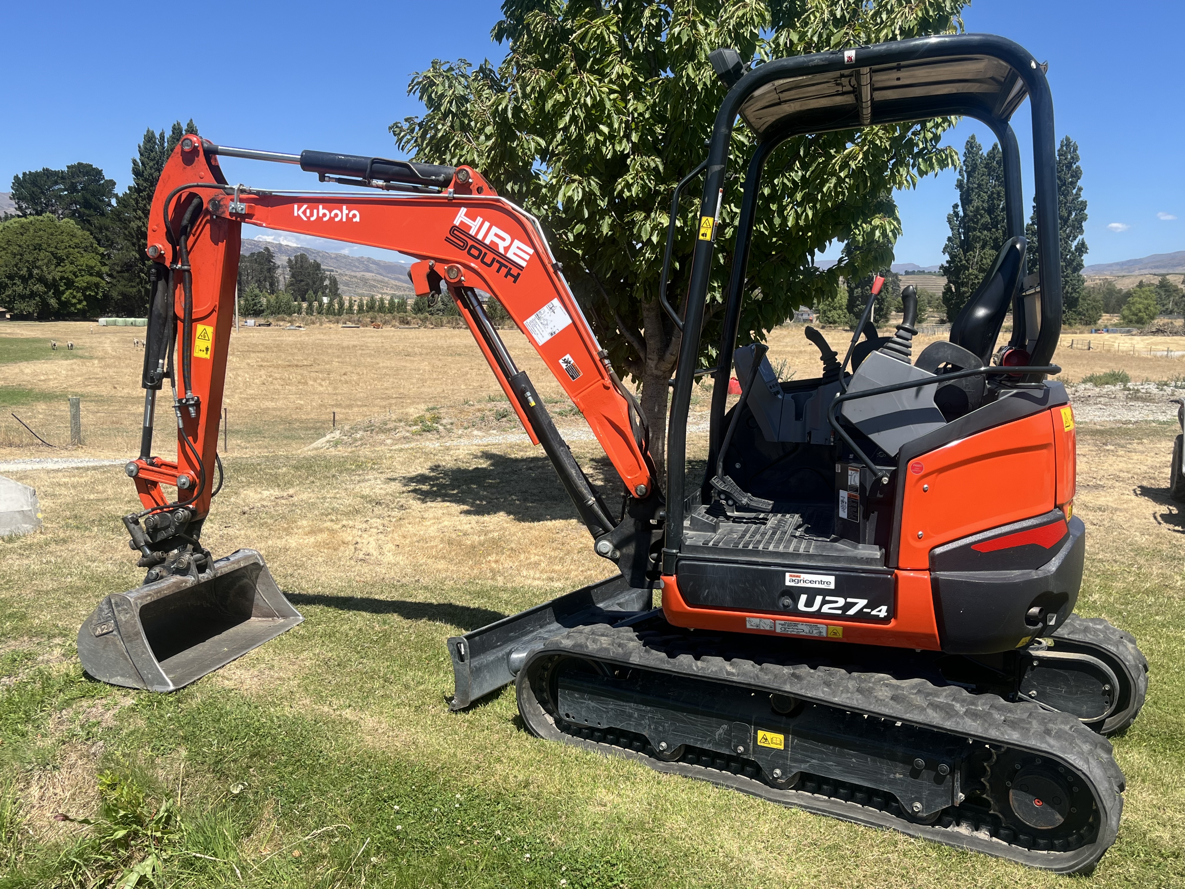 Rear of Hire South branded Kubota U17 mini digger with large Hire South logo displayed on the back panel, vineyard setting
