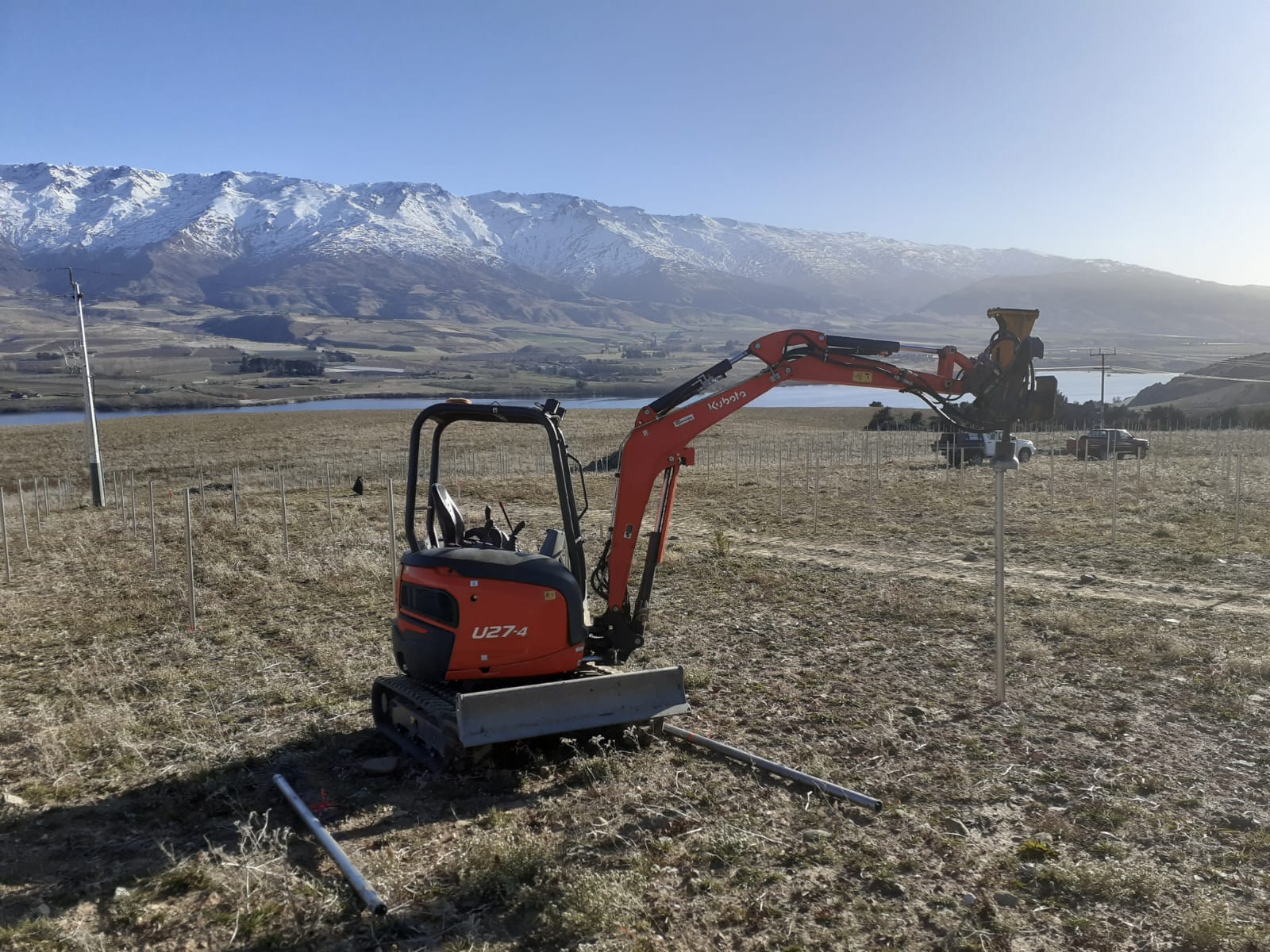 Hire South Kubota U27-4 digger in a frost-covered paddock on a clear Central Otago morning, with Lake Dunstan and snow-capped ranges visible behind